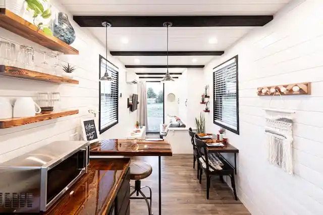 Bright tiny home interior with open shelving and a compact kitchen